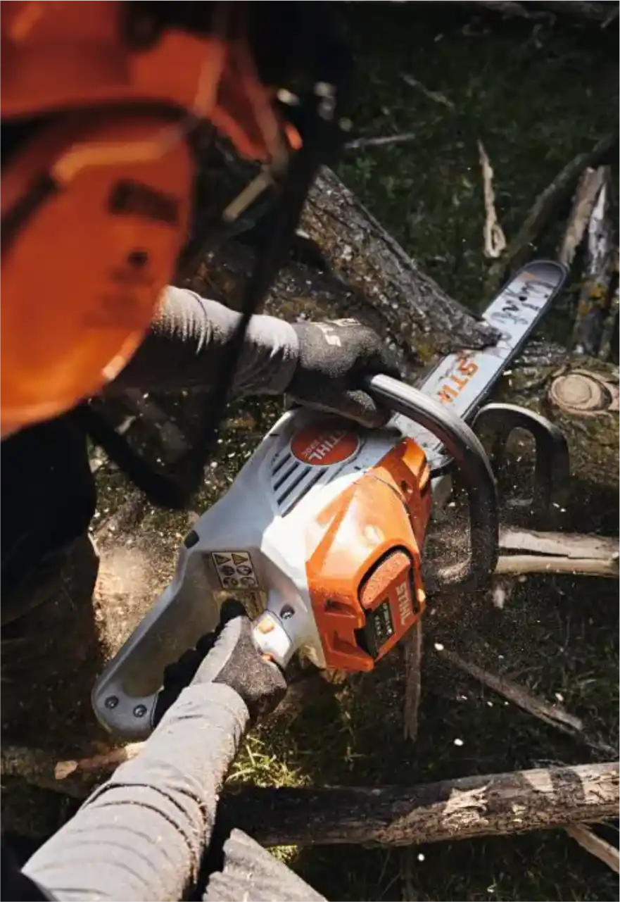 Operador com luvas cortando tronco com motosserra Stihl