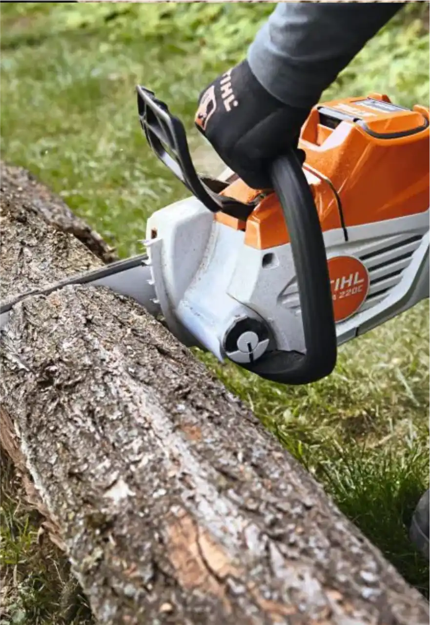 Operador com luvas cortando um tronco com motosserra a bateria Stihl