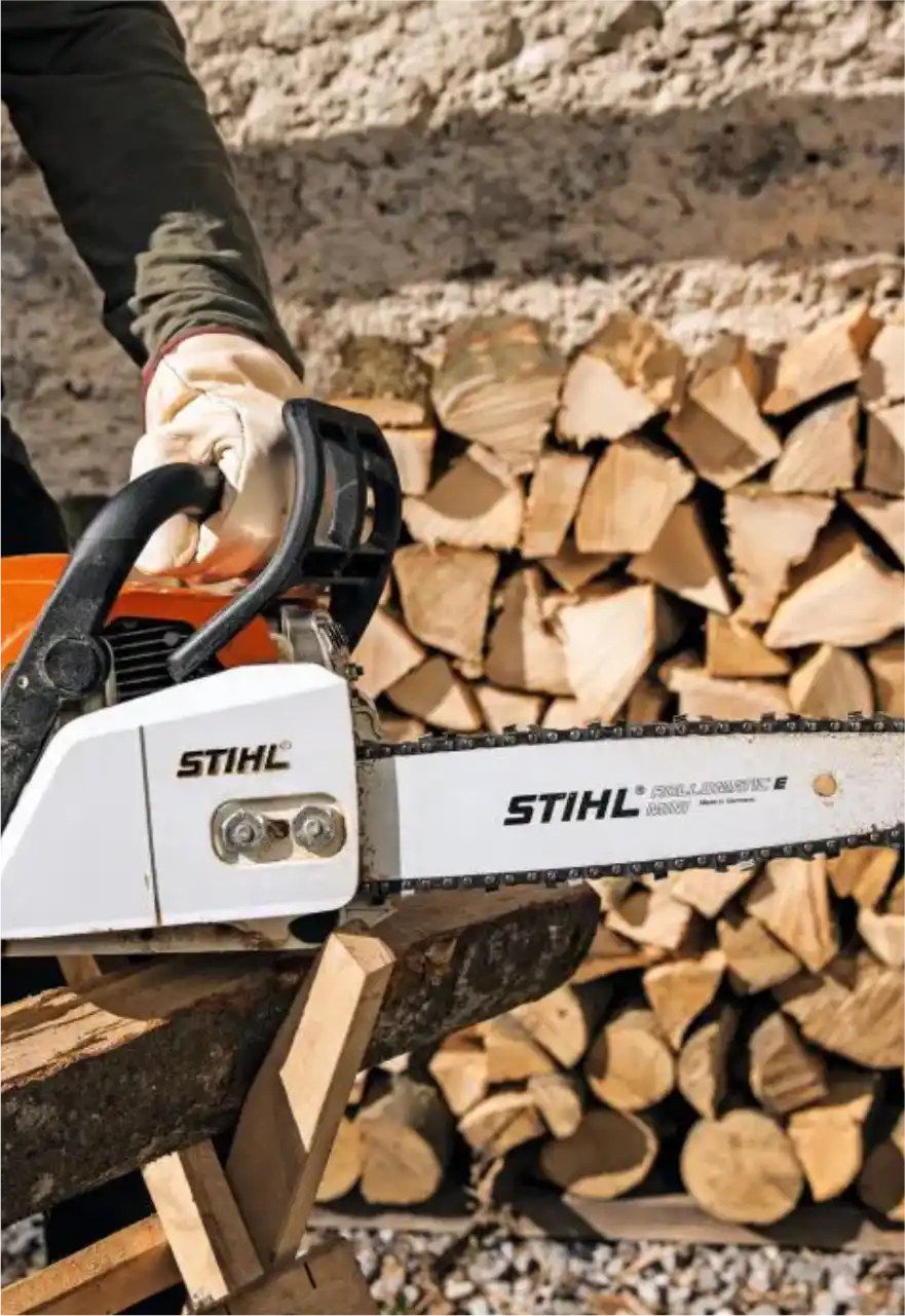 Motosserra Stihl apoiada sobre uma pilha de lenha cortada